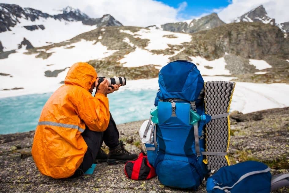 Mountaineer taking photo with pack