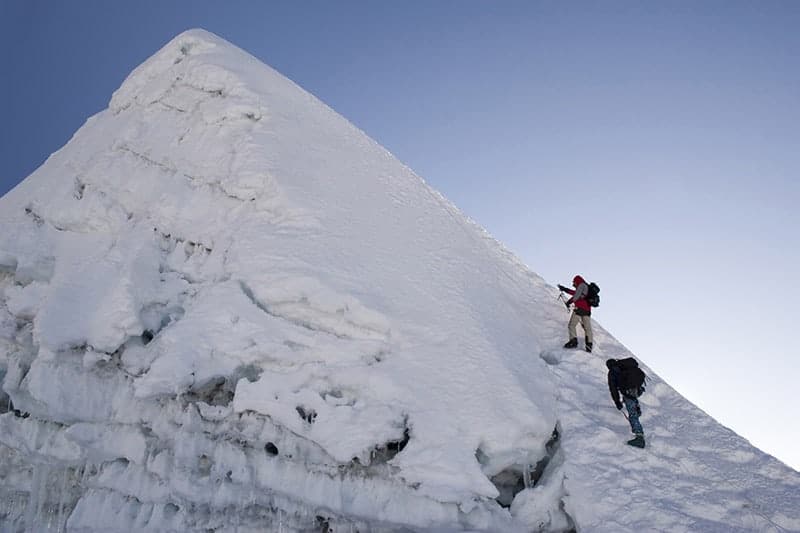 A horizontal image of two climbers on the side of Island Peak mountain.