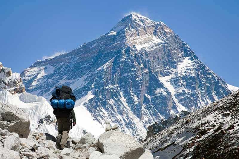 A horizontal image of a hiker trekking in the Himalayas with Kala Pattar in the background.