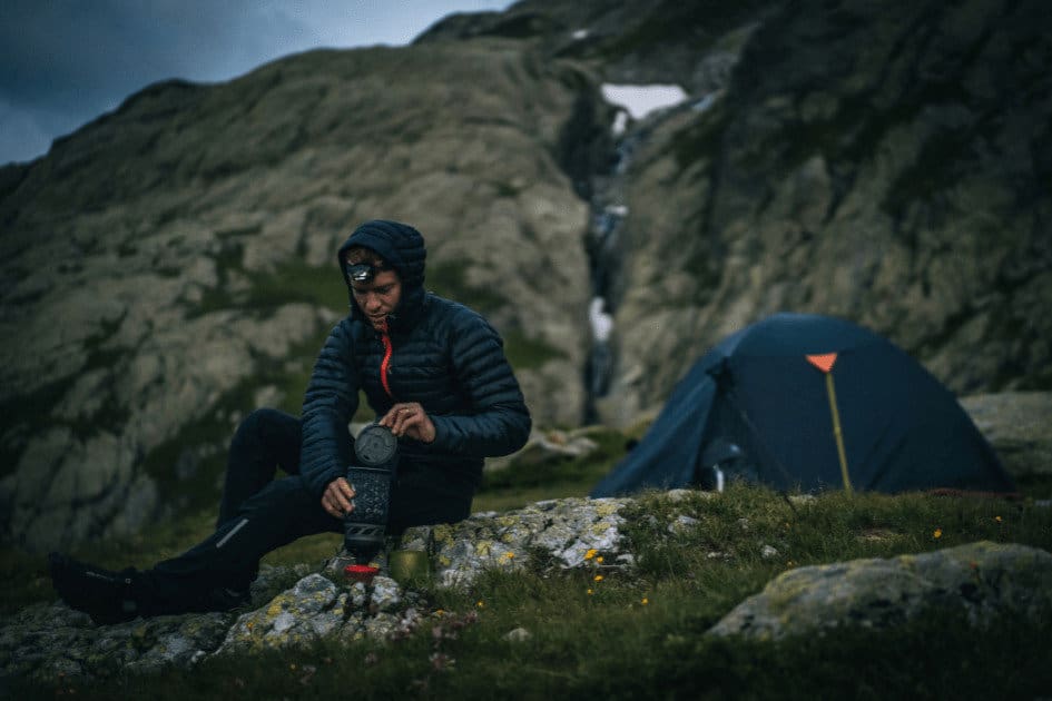 man cooking at night using a headlamp