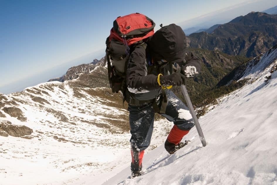 Mountain climber ascending snowy terrain with ice axe