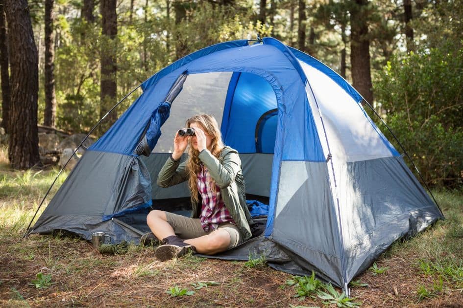 camper in tent using binoculars